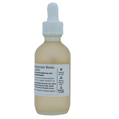 Glass dropper bottle of MCT & Frankincense Serum from The Homemaker’s Hustle. The label includes a farmhouse illustration and text describing a silky serum infused with frankincense resin. Net weight 2 oz.