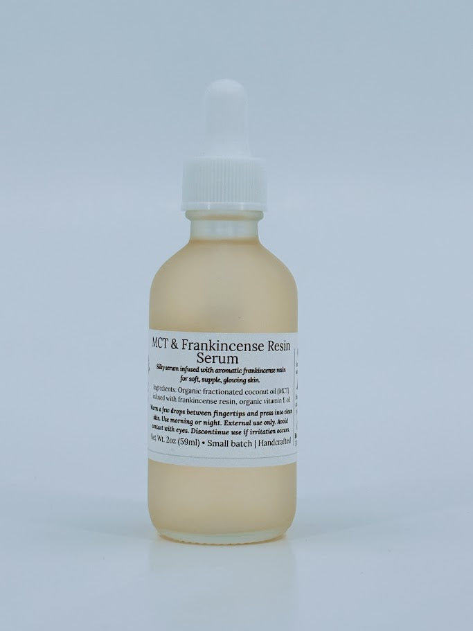 Glass dropper bottle of MCT & Frankincense Serum from The Homemaker’s Hustle. The label includes a farmhouse illustration and text describing a silky serum infused with frankincense resin. Net weight 2 oz.