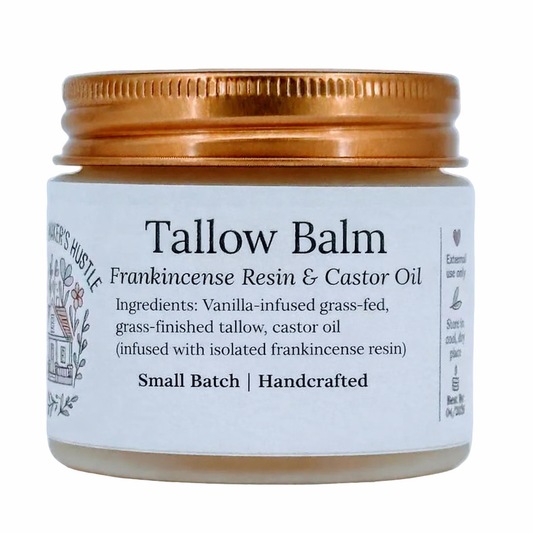Tallow balm in a frosted glass jar with a copper lid, labeled “Tallow Balm – Frankincense Resin & Castor Oil.” The white label lists ingredients including vanilla-infused grass-fed tallow and castor oil infused with frankincense resin, and notes “Small Batch | Handcrafted.”