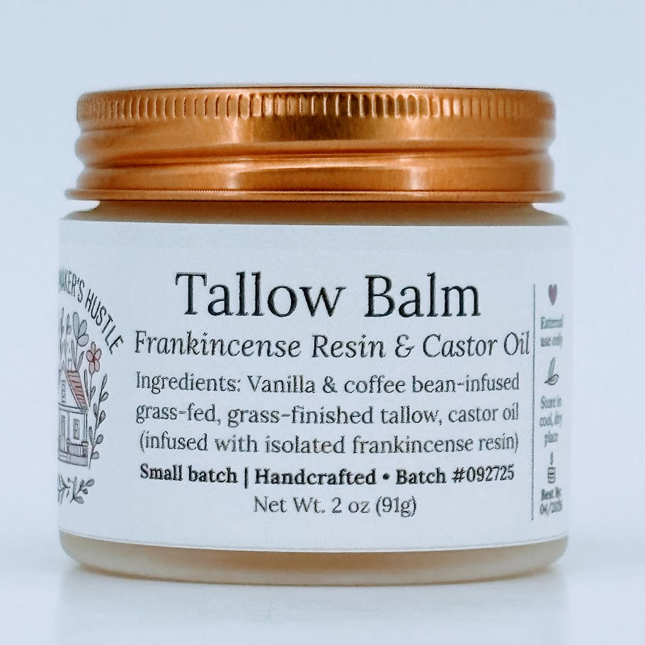 Glass jar of Tallow Balm with a copper-colored metal lid. The label reads ‘Tallow Balm – Frankincense Resin & Castor Oil’ and lists ingredients including vanilla- and coffee-bean-infused grass-fed tallow and castor oil. Net weight 2 oz.